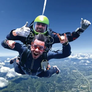 Saut en parachute tandem avec casque vert au-dessus des montagnes